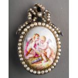 A continental silver brooch, set with a painted porcelain panel depicting cupids, in a seed pearl
