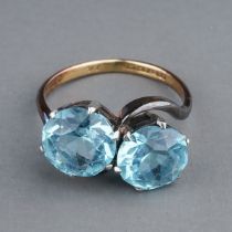 An early 20th century 18ct yellow gold and aquamarine two-stone cross-over ring, set with round