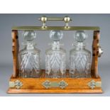 An early 20th Century EPNS mounted oak tantalus fitted with three cut glass spirit decanter with