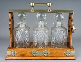 An early 20th Century EPNS mounted oak tantalus fitted with three cut glass spirit decanter with