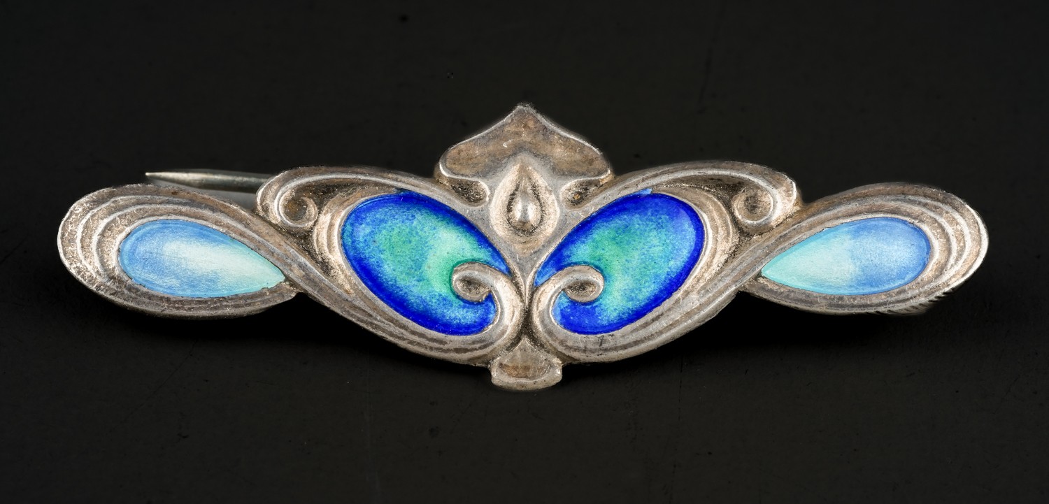An Art Nouveau silver and enamel bar brooch, four oval blue and green panels in sinuous lines,