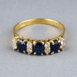 An 18ct yellow gold sapphire and diamond ring, set with three oval-cut sapphires and eight round