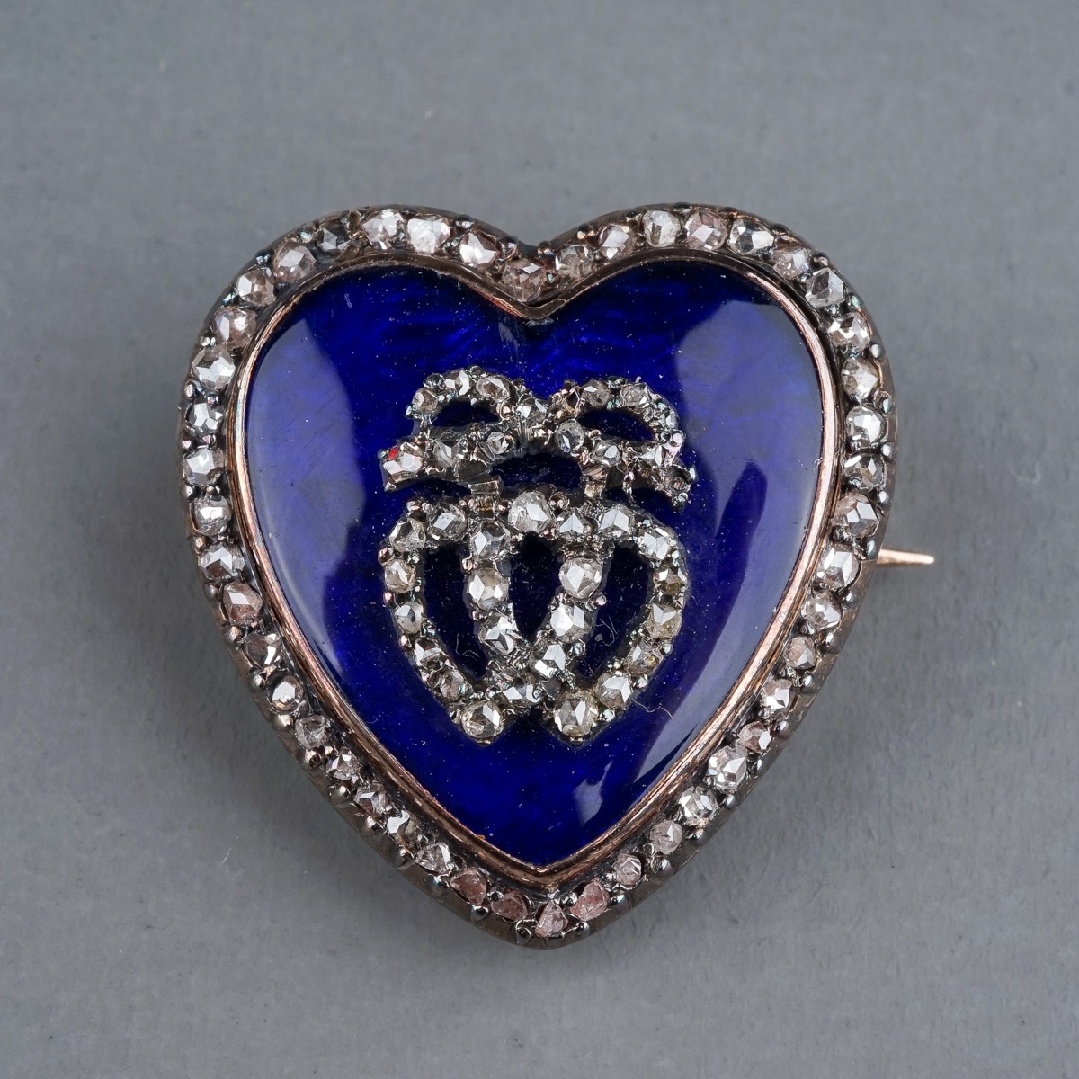 A late 19th century diamond and enamel heart shaped brooch/pendant, the blue enamel heart set with