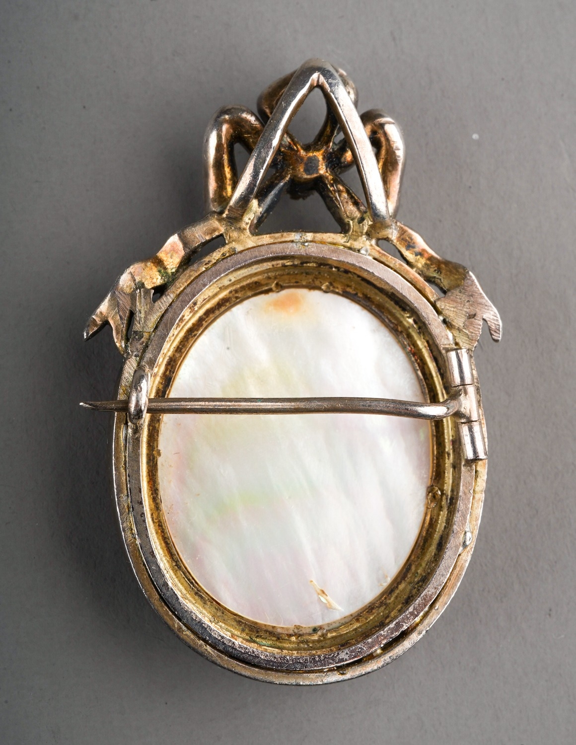 A continental silver brooch, set with a painted porcelain panel depicting cupids, in a seed pearl - Image 2 of 2