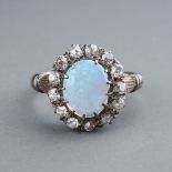 An Edwardian opal and diamond dress ring, set with an oval cabochon precious opal approx 7mm x 8.