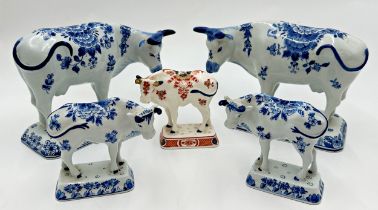 Two graduated pairs of Delft blue and white porcelain cows with a further Imari pattern example, the