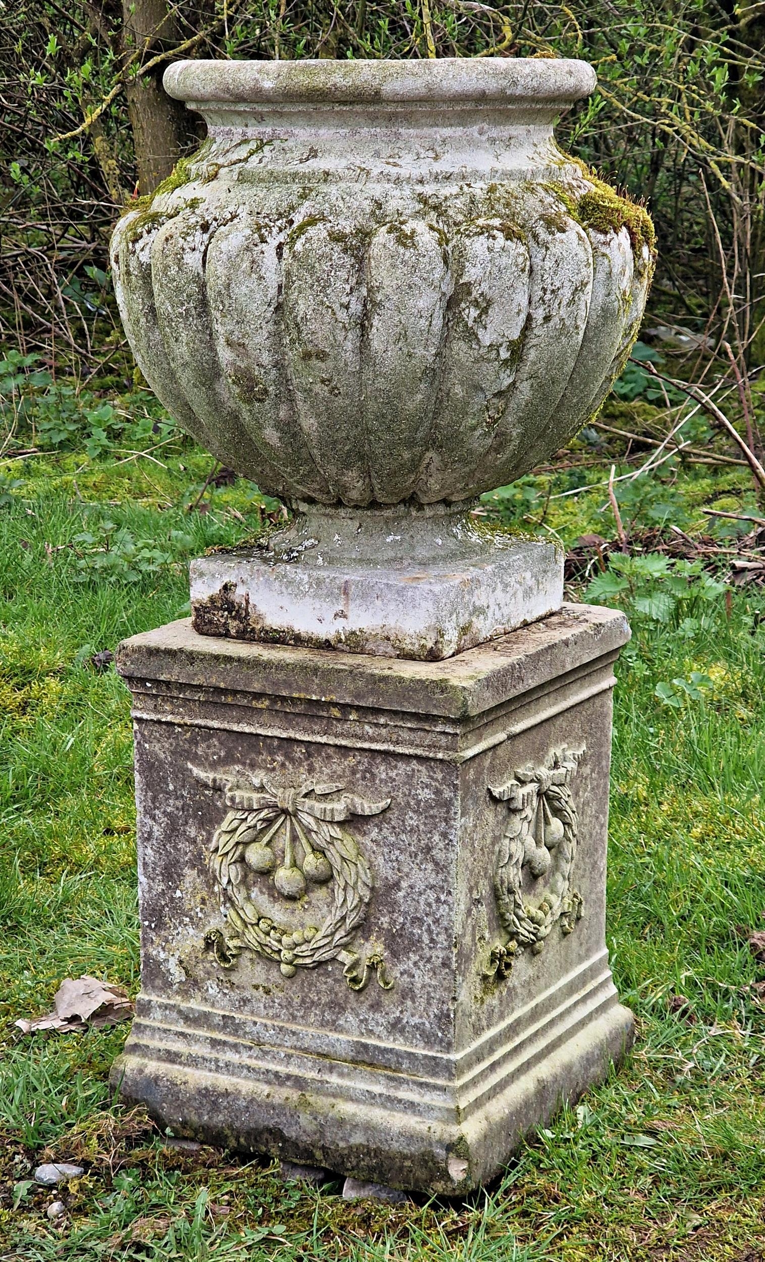 Well weathered reconstituted stone garden urn with lobed bowl raised on a square cut pedestal with