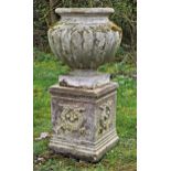 Well weathered reconstituted stone garden urn with lobed bowl raised on a square cut pedestal with