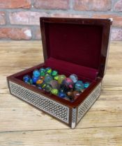 Vintage pearl inlaid casket holding a collection of antique marbles