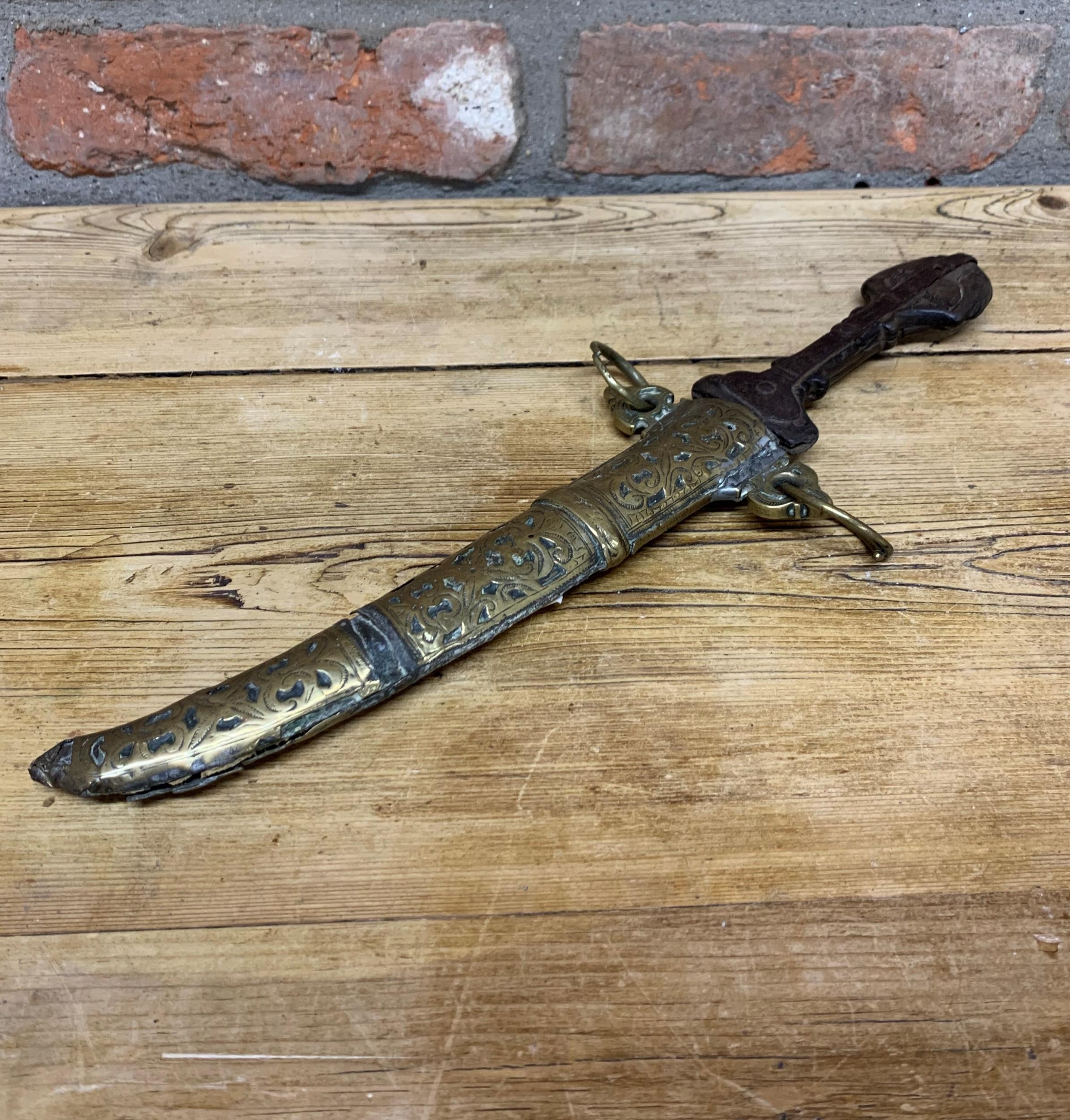 19th century Jambiya dagger with iron blade and carved wooden hilt, held in a decorative scrolled