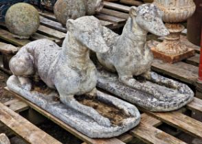 A pair of weathered reconstituted stone garden ornaments of recumbent greyhounds, H 38cm x W 69cm