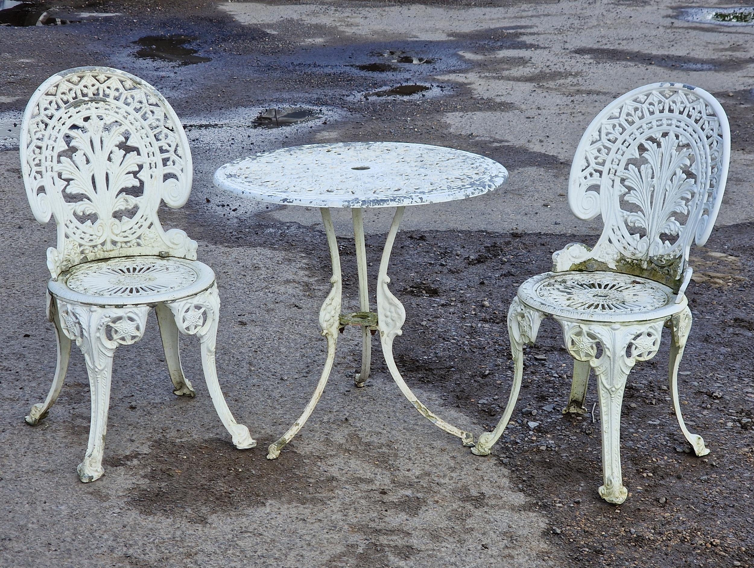 A painted cast metal three piece garden terrace set to include a table and two chairs with pierced