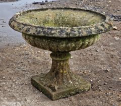 A weathered reconstituted stone two sectional garden urn with lobed bowl and flared egg and dart