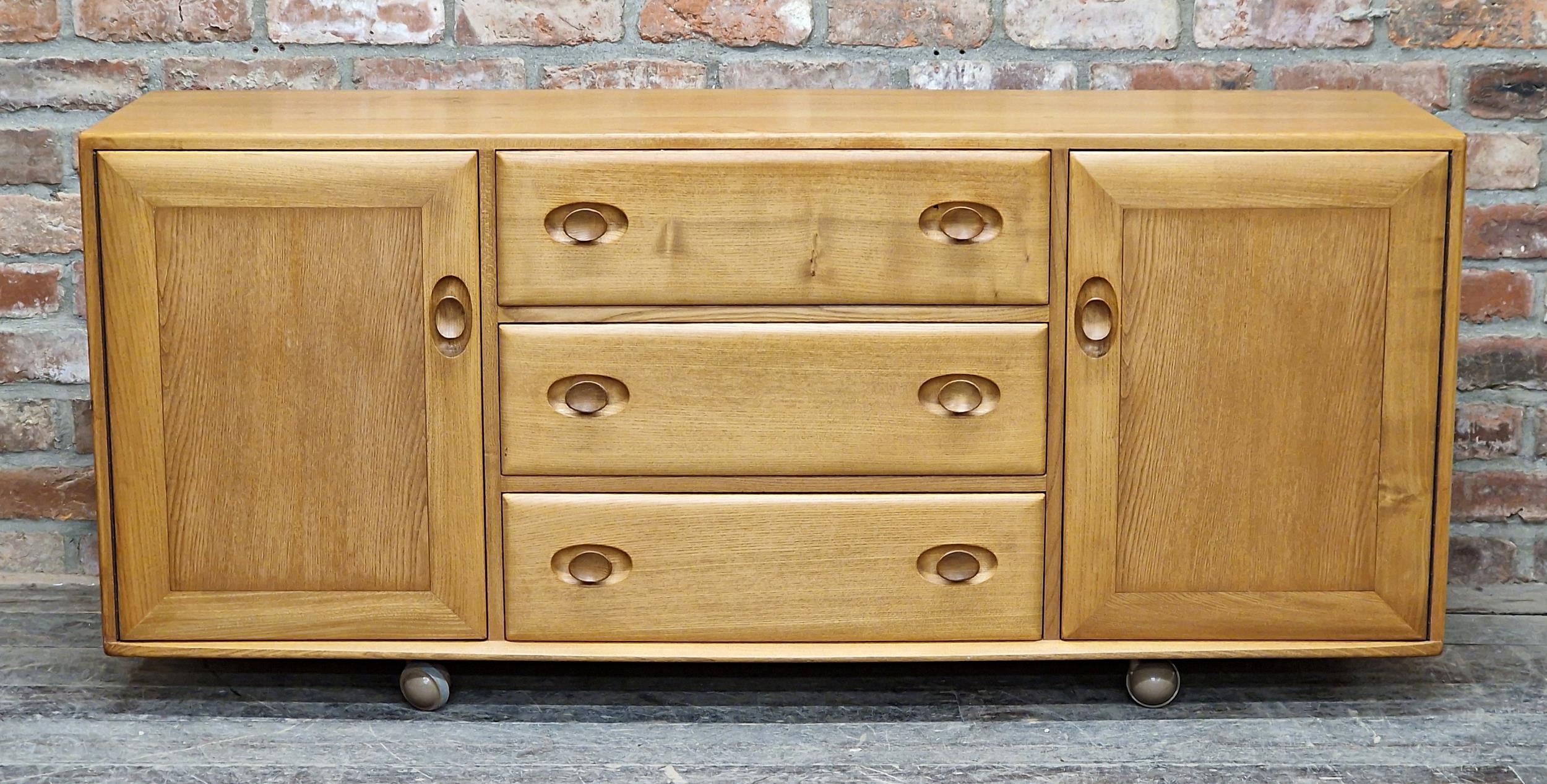 Ercol light elm sideboard fitted with three draws flanked by two cupboard doors, H 69cm x W 156cm