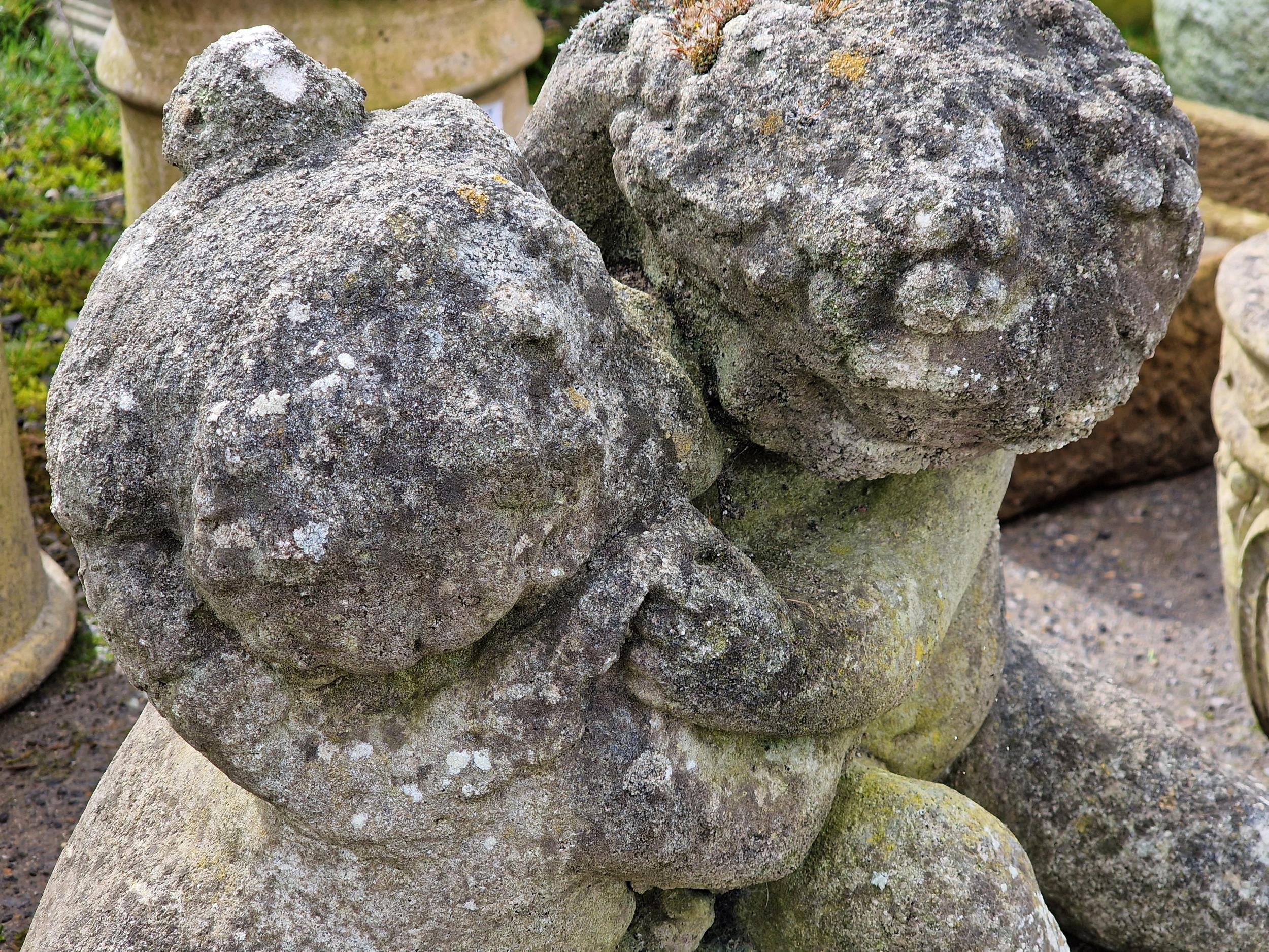 A weathered reconstituted stone garden ornament of cherubs embracing, H 45cm x W 66cm - Image 2 of 2