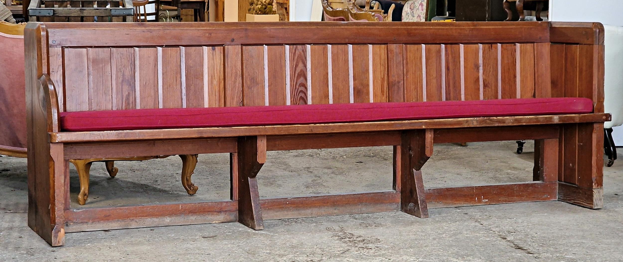 A pitch pine church pew with cushion, H 83cm x W 240cm