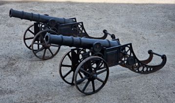 A pair of cast iron cannons raised on elevated carriages with spoked wheels, incised 'RMI', H 64cm x
