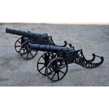 A pair of cast iron cannons raised on elevated carriages with spoked wheels, incised 'RMI', H 64cm x