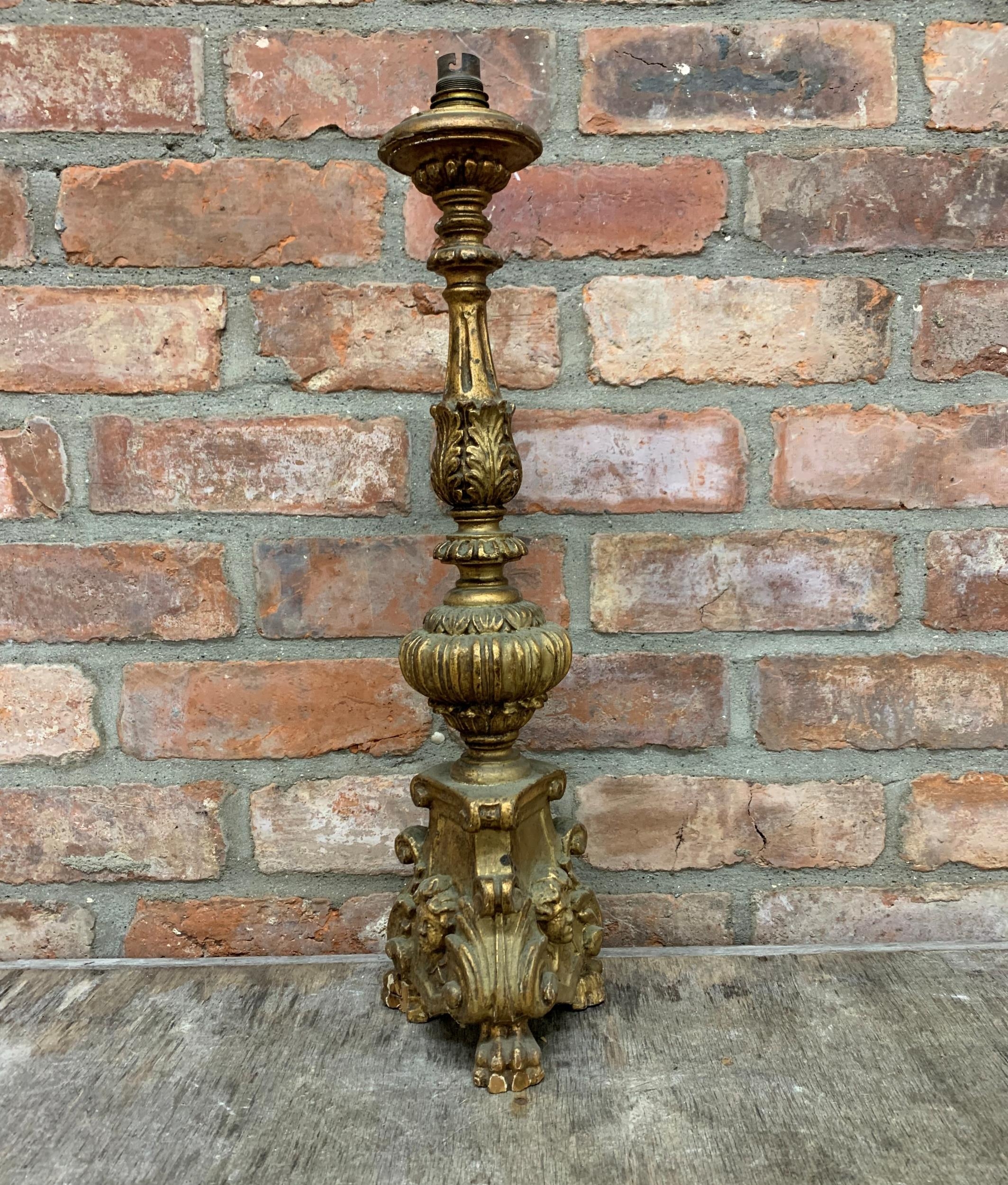 Carved gilt pricket stick lamp base with lion paw feet and cherub face decoration, H 62cm