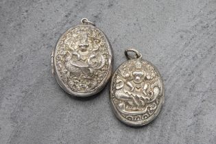 Two similar Anglo-Indian silver locket pendants, each decorated in relief by a seated deity, the