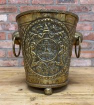 Large brass coal bucket with Aztec face mask and sundial embossing atop three ball feet with