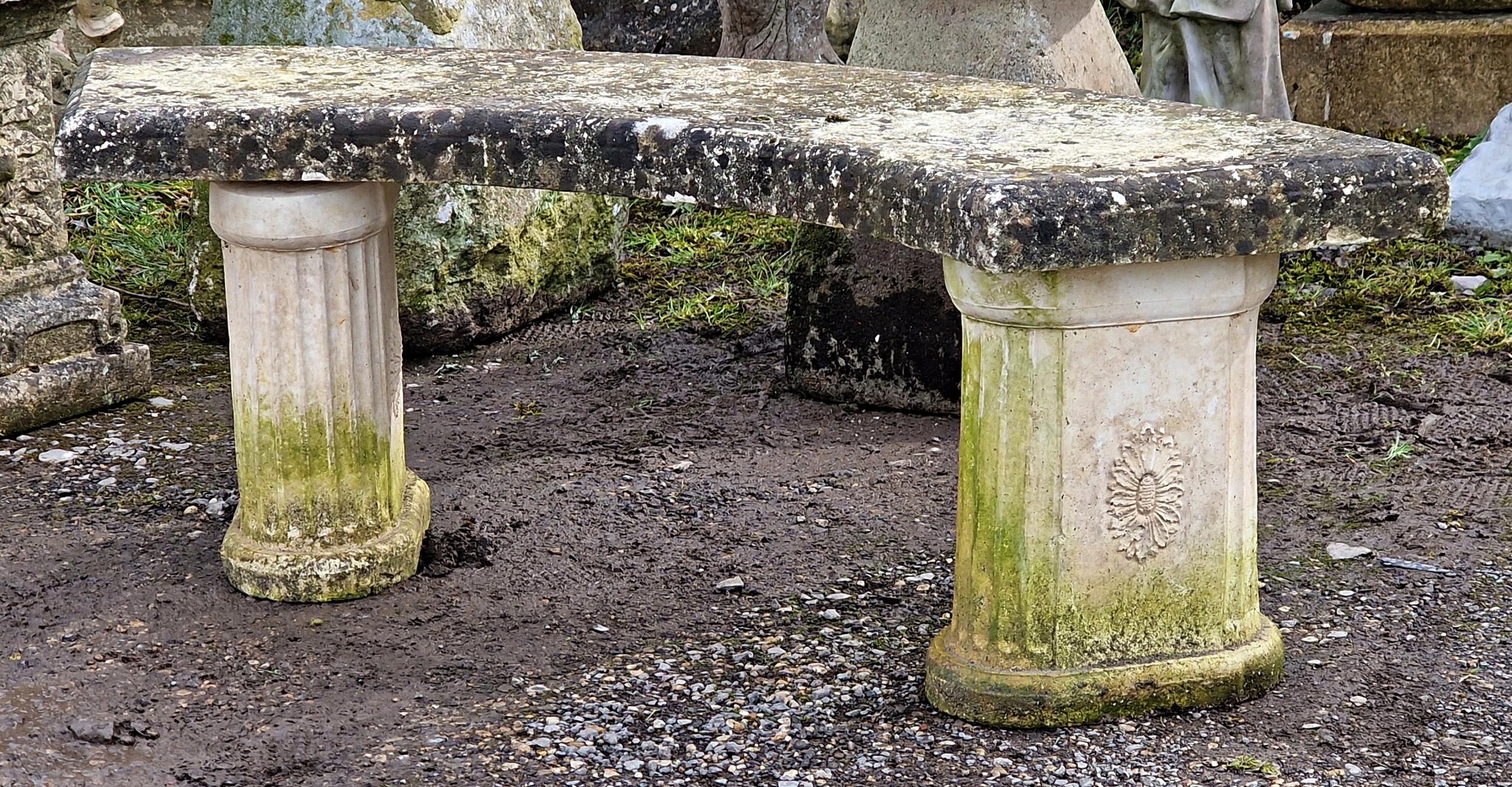 A reconstituted stone three piece garden bench with curved top raised on fluted pedestal supports, H