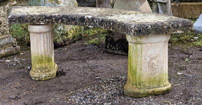 A reconstituted stone three piece garden bench with curved top raised on fluted pedestal supports, H