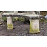 A reconstituted stone three piece garden bench with curved top raised on fluted pedestal supports, H