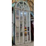 A large antique reclaimed wooden Gothic church window of arched form fitted with mirrored panels,