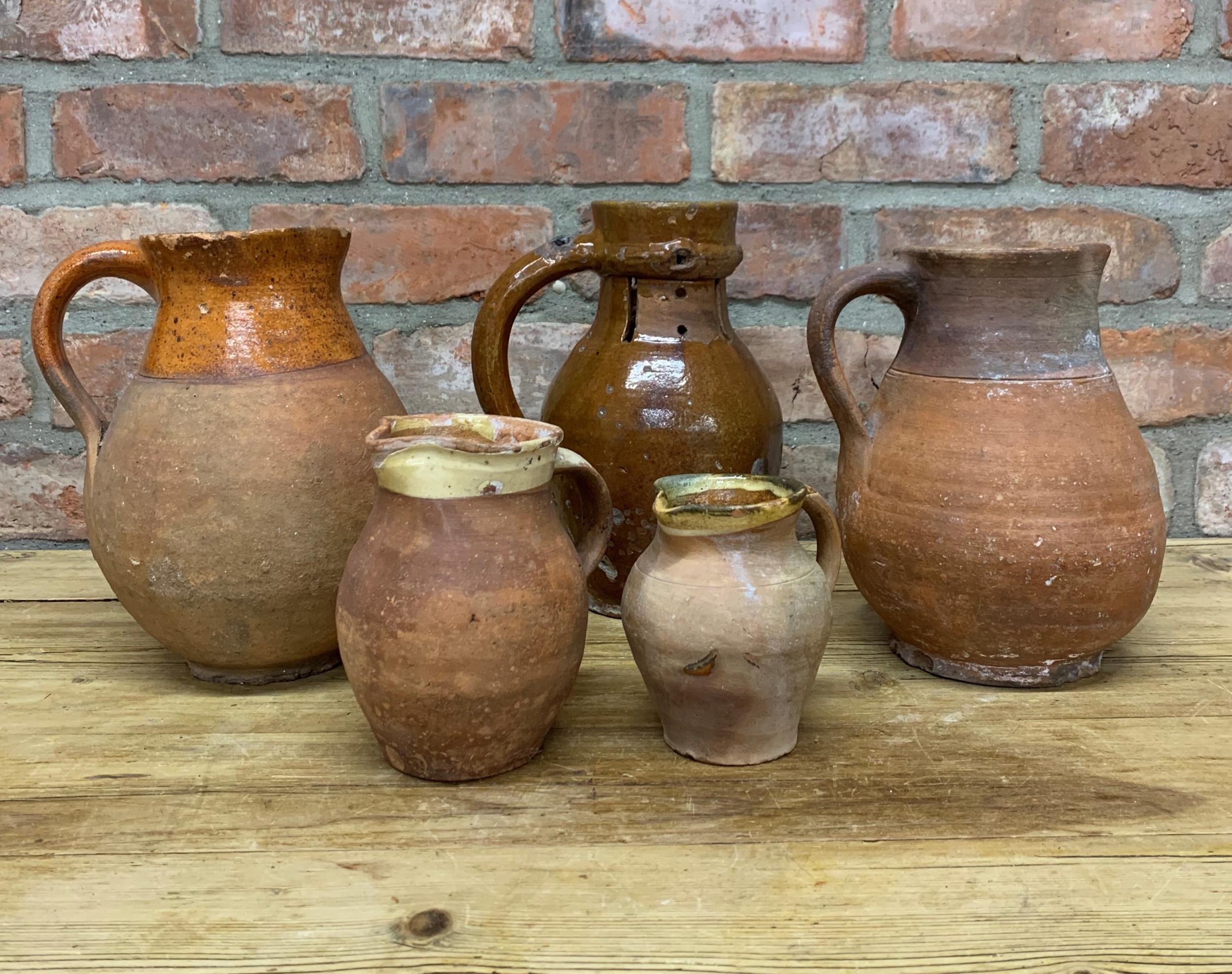 Four antique 18th Somerset glazed earthenware pitcher jugs with additional glazed puzzle jug