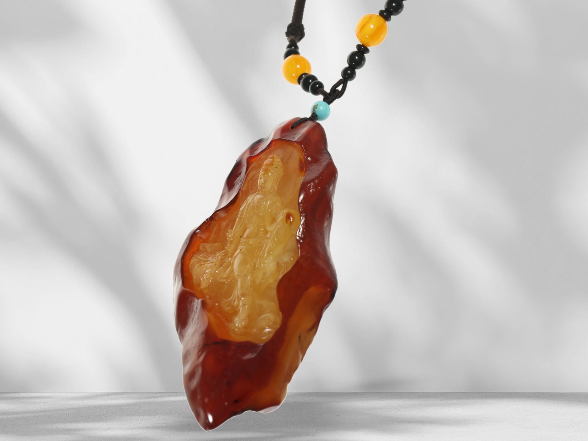 Amber: large, cut butterscotch amber of approx. 550ct on a fabric band, "Buddha" motif