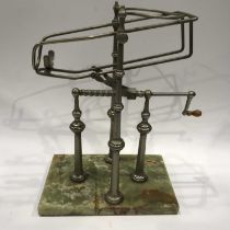 A metal wine decanting cradle, corkscrew winding mechanism with wooden handle, on four knopped