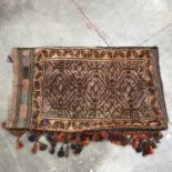 A Kilim tribal carpet bag, tassel fringe, geometric design with leaf border on red ground, 107 by