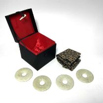 A set of four Chinese green jade type ring discs, together with fabric napkins, in satin covered