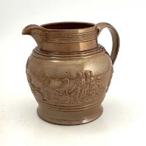 A large brown glazed jug, circa 1820, relief moulded with rural hunting scene. 23 cm tall.