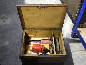 A vintage wooden first aid box, leather strap handle, some contents including bandages, wooden
