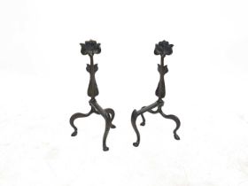 A pair of Arts and Crafts cast bronze fire dogs, int the form of stylised tulips, on serpentine