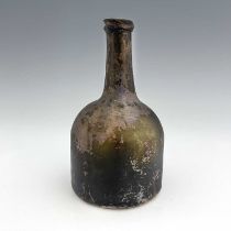 An early 18th century glass wine bottle, squat mallet form, oxidised patination, 21cm high