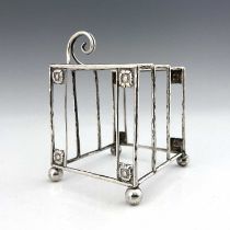 A E Jones, an Arts and Crafts silver three division toast rack, Birmingham 1918, planished wire