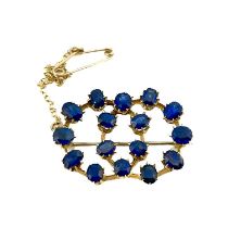 A gold and sapphire brooch, two interlocking rings of facet cut blue gem stones, 3cm long, 6.1g