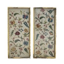 A pair of crewelwork panels, early 18th Century, depicting polychrome trailing floral foliage on a