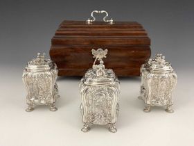 A suite of George II Rococo silver tea caddies and sugar box, each of bombe form with four cast