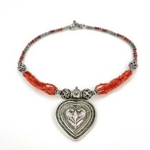 A silver and coral necklace, possibly Central American, the heart shaped pendant of concentric