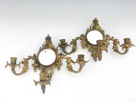 A pair of gilt metal girandoles, late 19th Century, of Rococo design, circular looking glasses,