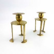 A pair of Arts and Crafts brass candlesticks, in the style of C F A Voysey, 1906, each with three