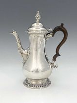 A George III silver coffee pot, of baluster form, with cast and applied spout, surmounted by foliate