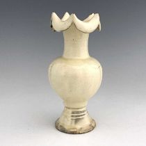 A Chinese cream glazed earthenware vase, probably Tang, the melon form ovoid body with wave