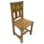 An Arts and Crafts oak and tile chair, possibly Leonard Wyburd for Liberty and Co., turned and