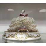 A Capo Di Monte porcelain lacework figure of a lady, seated with elaborate tulle skirts, on circular