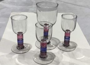 Four studio glass wine glasses, three port glasses and a goblet, multi-coloured stems,